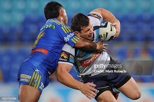 Greg Bird of the Titans is tackled by Chris Sandow of the Eels during the round 20 NRL match between the Gold Coast Titans and the Parramatta Eels at...