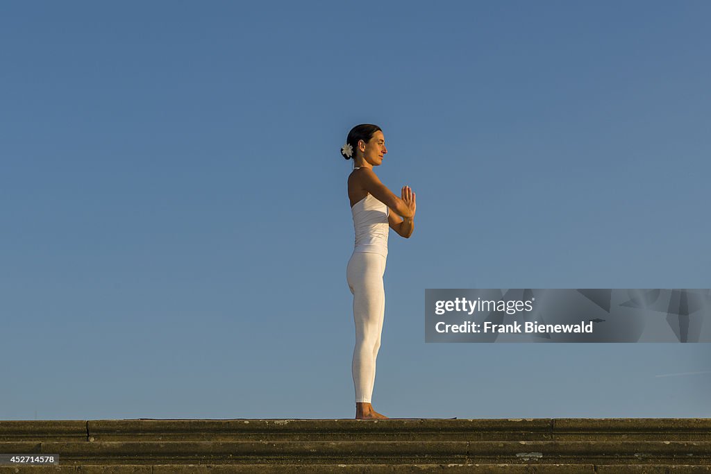 Young woman, wearing a white body suit, is practising Hatha-...