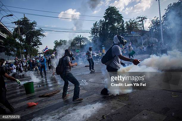 Riot police fire tear gas as anti-government protesters try to remove a barricade and occupy the government house on December 1, 2013 in Bangkok,...