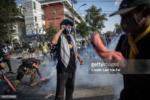 Riot police fire tear gas as anti-government protesters try to remove a barricade and occupy the government house on December 1, 2013 in Bangkok,...