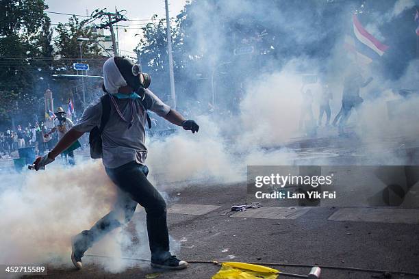 Riot police fire tear gas as anti-government protesters try to remove a barricade and occupy the government house on December 1, 2013 in Bangkok,...