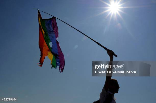 Gay rights activist waves a damaged rainbow flag during a gay pride in St. Petersburg on July 26, 2014. AFP PHOTO / OLGA MALTSEVA