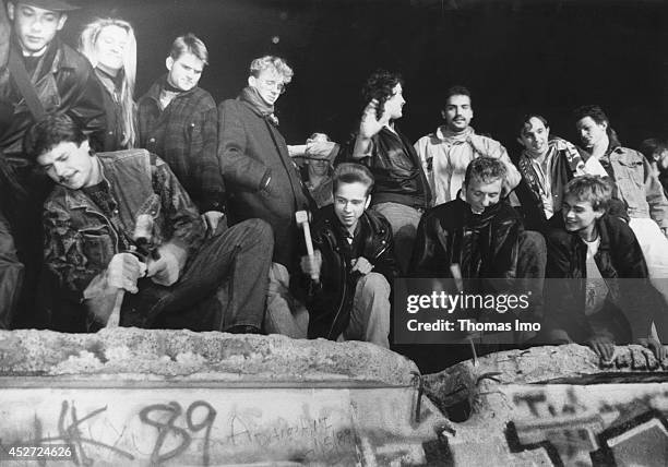 Young people start tearing down the Berlin Wall after opening of the border on November 09 in Berlin, Germany. The year 2014 marks the 25th...