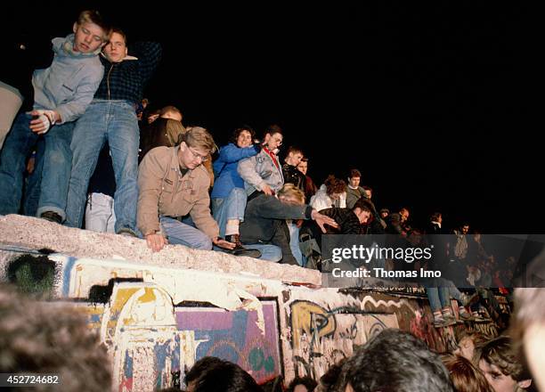 People climbing on the Berlin Wall after opening of the border on November 09 in Berlin, Germany. The year 2014 marks the 25th anniversary of the...