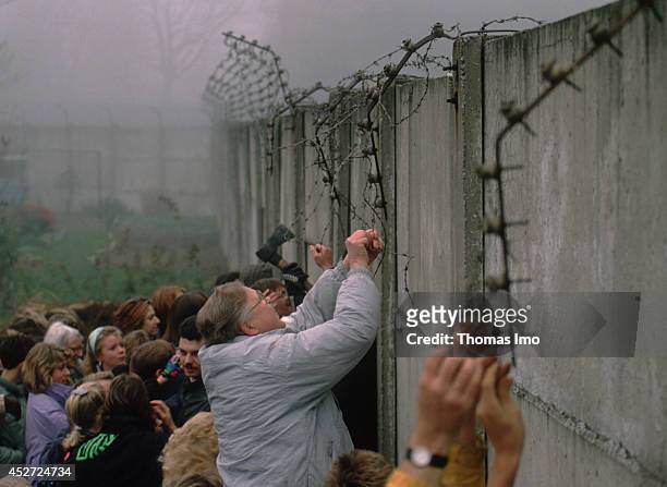 People tearing down barb wire from the Berlin Wall after opening of the border on November 09 in Berlin, Germany. The year 2014 marks the 25th...