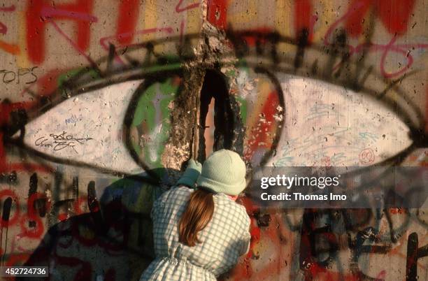 Woman looking through a whole of the Berlin Wall after opening of the border on November 09 in Berlin, Germany. The year 2014 marks the 25th...