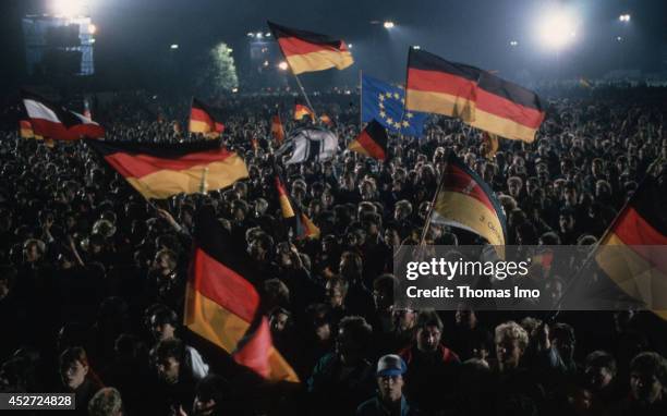 People celebrating the German Unity Day and are waving German Flags on October 03 in Berlin, Germany. The year 1990 marks the 25th anniversary of the...