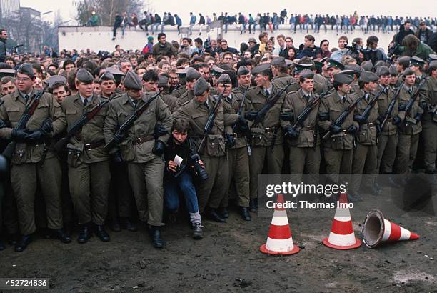 Photographer pushing through border guards of the German Democratic Republic, who are trying to keep back the mass of people on November 09 in...