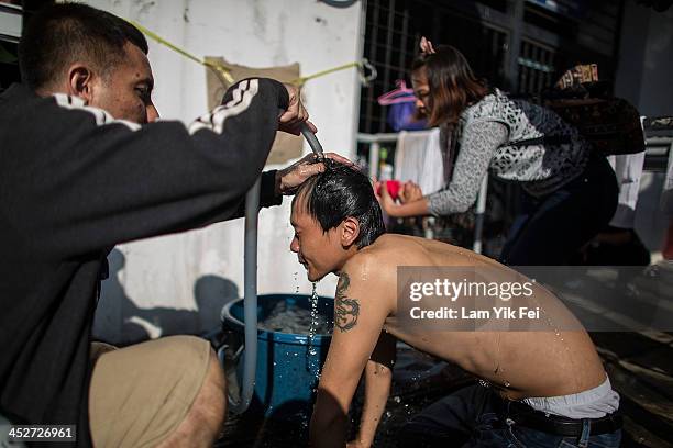 Protestors wash the eyes of anti-government protester suffering from exposure to tear gas fired by riot police on December 1, 2013 in Bangkok,...