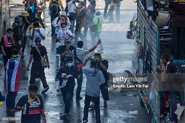 Anti-government protesters escape after riot police fire tear gas on December 1, 2013 in Bangkok, Thailand. Anti-government protesters in Bangkok say...