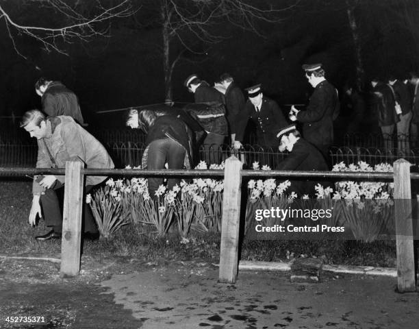 Police search for evidence in flower beds by the Mall, following an attempt, earlier that evening, to kidnap Princess Anne, London, 20th March 1974....