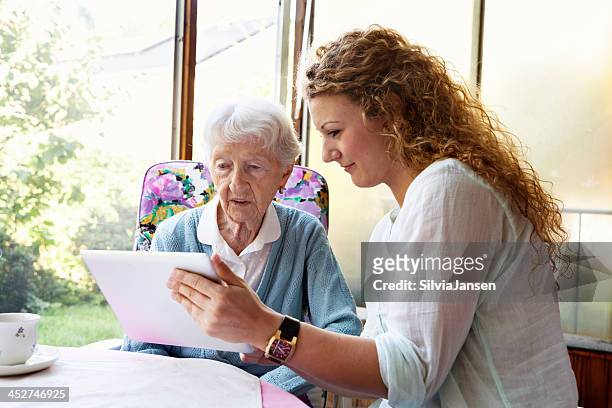 donna anziana e digital tablet - assistenza ai bisognosi foto e immagini stock