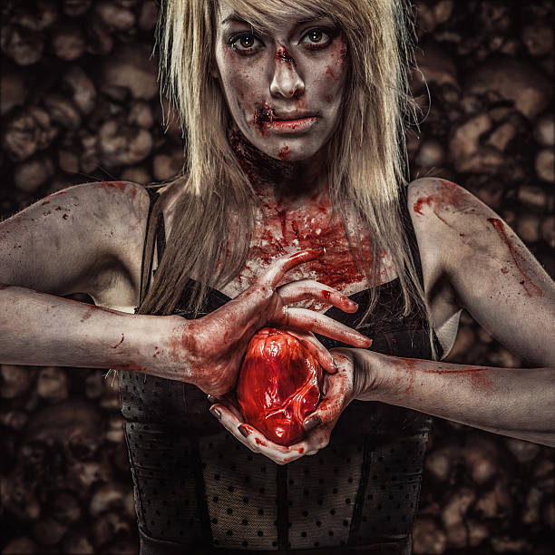 young zombie woman holding a human heart - bleeding scared heart stock pictures, royalty-free photos & images