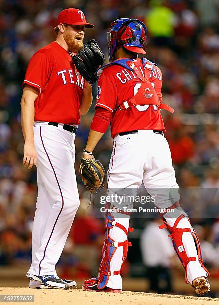 Pitcher Nate Adcock of the Texas Rangers talks with Robinson Chirinos of the Texas Rangers while pitching against the Oakland Athletics in the top of...