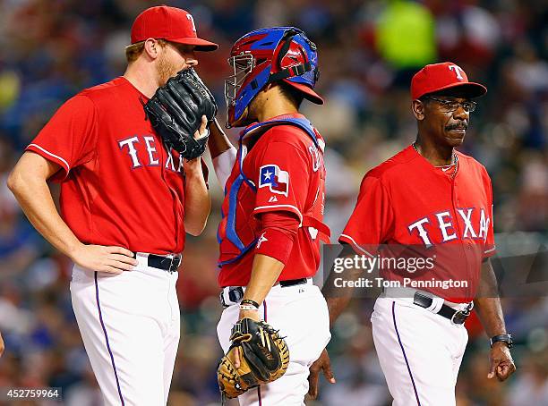 Pitcher Nate Adcock of the Texas Rangers talks with Robinson Chirinos of the Texas Rangers as manager Ron Washington of the Texas Rangers visits the...