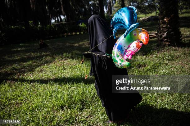 Woman from an Islamic commune An-Nadzir holds balloons after Eid Al Fitr mass prayer at Mawang Lake on July 27, 2014 in Gowa, South Sulawesi,...