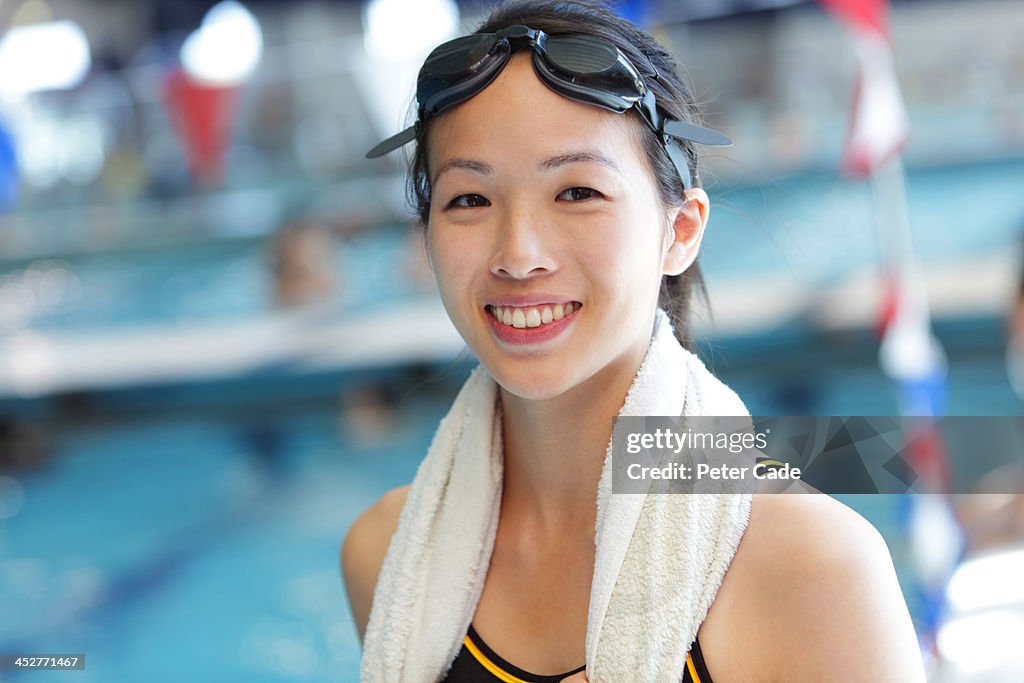 Young smiling woman stood by swimming pool