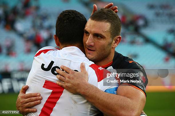 Former team mates Benji Marshall of the Dragons and Robbie Farah of the Tigers embrace after the round 20 NRL match between the Wests Tigers and the...