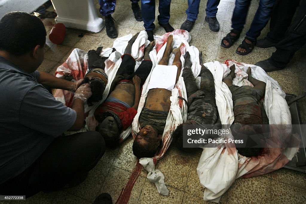 Palestinian relatives mourn over the bodies of children from...