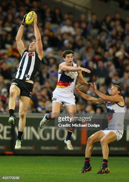 Travis Cloke of the Magpies marks the ball against Ricky Henderson and Daniel Talia of the Crows during the round 18 AFL match between the...
