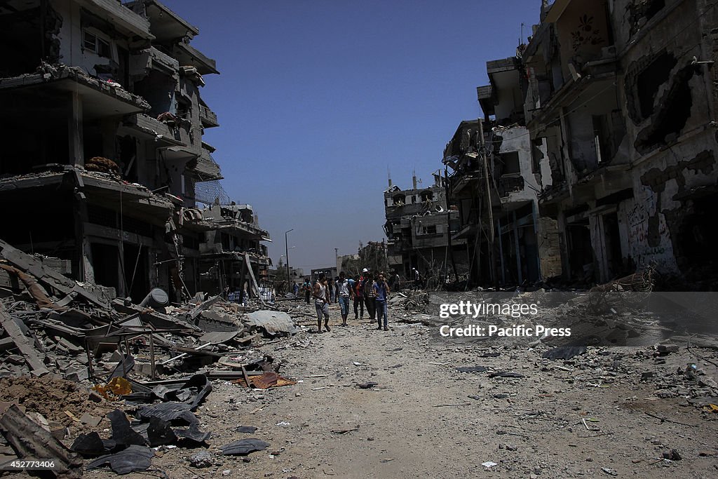 Palestinians inspect the rubble of destroyed houses in the...