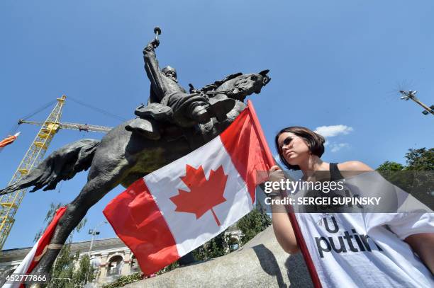Woman holds a Canadian flag near the equestrian statue of Petro Konashevych-Sahaidachny on Kontraktova Square in Kiev as diplomats and employees of...