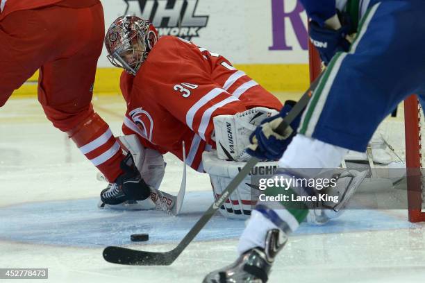 Cam Ward of the Carolina Hurricanes watches as Ryan Kesler of the Vancouver Canucks scores a goal at PNC Arena on December 1, 2013 in Raleigh, North...