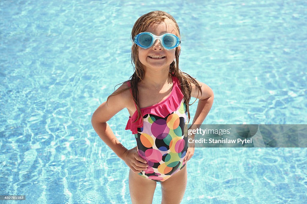 Small girl standing near swimming pool