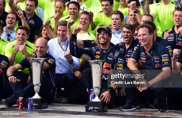 Daniel Ricciardo of Australia and Infiniti Red Bull Racing celebrates victory with the trophy and members of his team including Infiniti Red Bull...