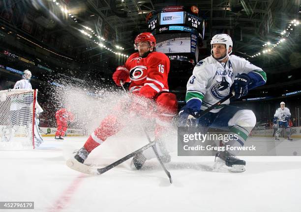 Tuomo Ruutu of the Carolina Hurricanes battles for a loose puck with Kevin Bieksa of the Vancouver Canucks during their NHL game at PNC Arena on...