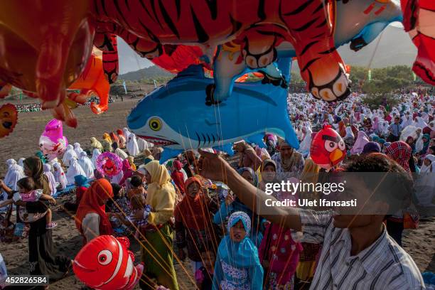 Man sells balloons as Indonesian muslims attend Eid Al-Fitr prayer on 'sea of sands' at Parangkusumo beach on July 28, 2014 in Yogyakarta, Indonesia....