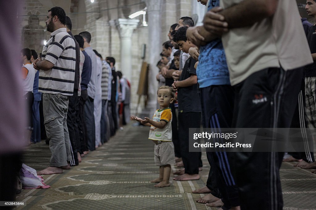 A Palestinian boy with his father join  the prayer in the...