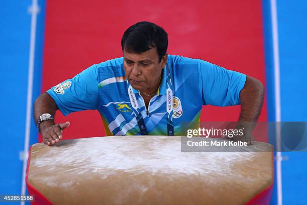 Coach from India spits on the vault as he prepares it for his competitor in the Women's Team Final & Individual Qualification at the SECC Precinct...