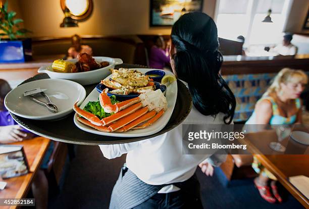 Waitress carries a tray a lobster kettle and a crab trio dish at a Red Lobster restaurant in Yonkers, New York, U.S., on Thursday, July 24, 2014....