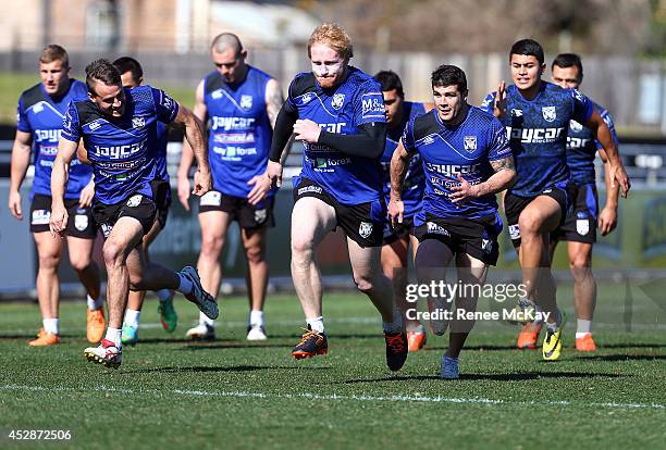 Josh Reynolds, James Graham and Michael Ennis race during a Canterbury Bulldogs NRL training session at Belmore Sports Ground on July 29, 2014 in...