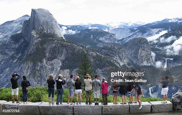 Visitors look out at Yosemite National Park from Glacier Point on July 21, 2014 in Yosemite National Park, California. Yosemite is among California's...