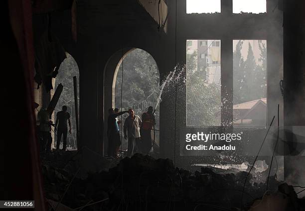 Palestinian firefighters try to extinguish fire on the rubble of a El-Emin Mohammed mosque after an Israeli air strike in Gaza City, Gaza on July 29,...