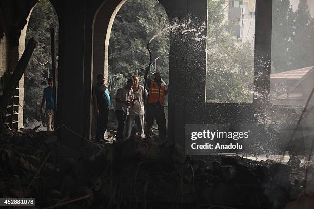 Palestinian firefighters try to extinguish fire on the rubble of a El-Emin Mohammed mosque after an Israeli air strike in Gaza City, Gaza on July 29,...