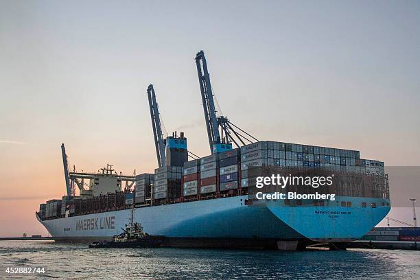 Shipping containers stand aboard the Maersk Mc-Kinney Moller Triple-E Class container ship, operated by A.P. Moeller-Maersk A/S, as it is guided to...