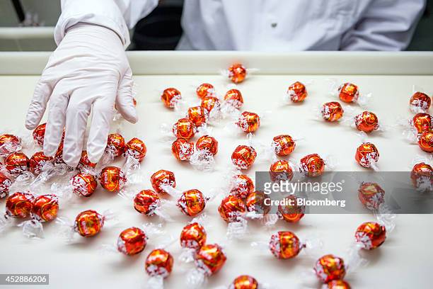 An employee checks wrapped Lindor chocolate balls as they sit on the production line inside the Lindt & Spruengli AG factory in Kilchberg,...