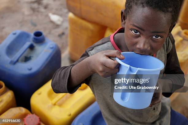 Boy with water cans and a jar at a waterhole on April 20 in Fada N'gourma, Burkina Faso.