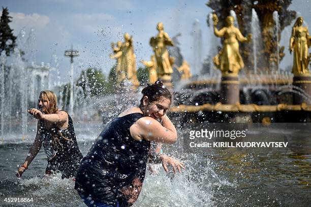 Young people splash water at each other while standing in the pool of famous "Druzhba narodov" fountain at the VDNKh, a public park and exhibition...