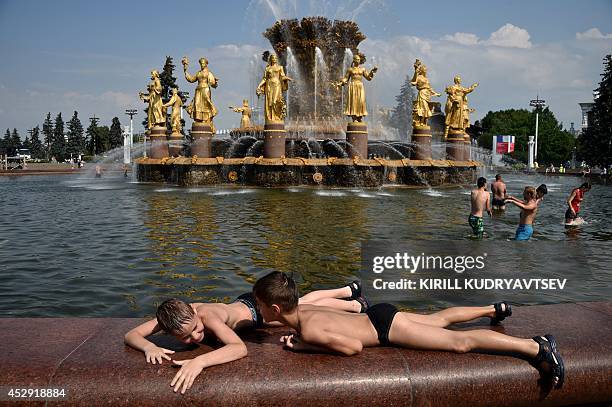 Young people cool themselves in the pool of famous "Druzhba narodov" fountain at the VDNKh, a public park and exhibition space, in Moscow, on July...