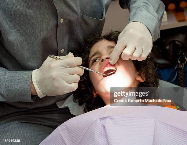 Dentist doctor examines a child's problematic tooth in dentistry office, child in a dentist chair.