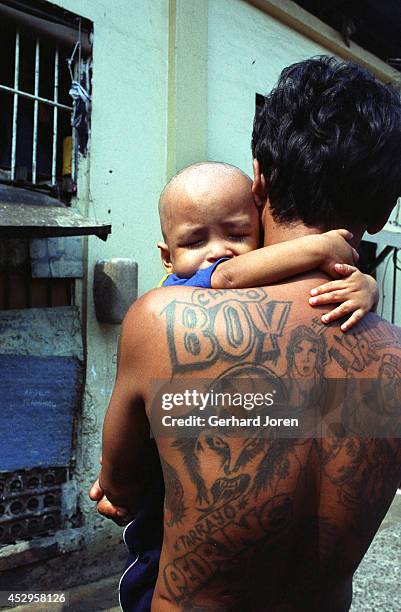 Young child hangs on to a member of the Batang City Jail gang. A number of children live with their fathers in their cells. Relatives of the inmates...