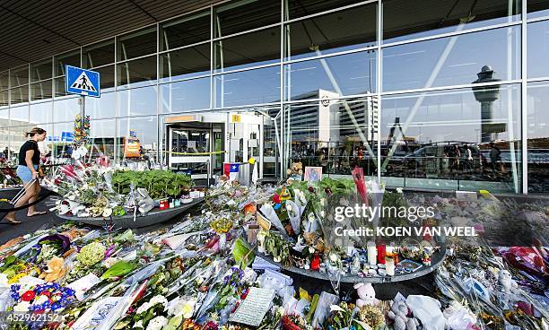 Woman walks past flowers, candles and stuffed animals placed at Schiphol Airport, near Amsterdam, the Netherlands, on July 31 in memory of the...