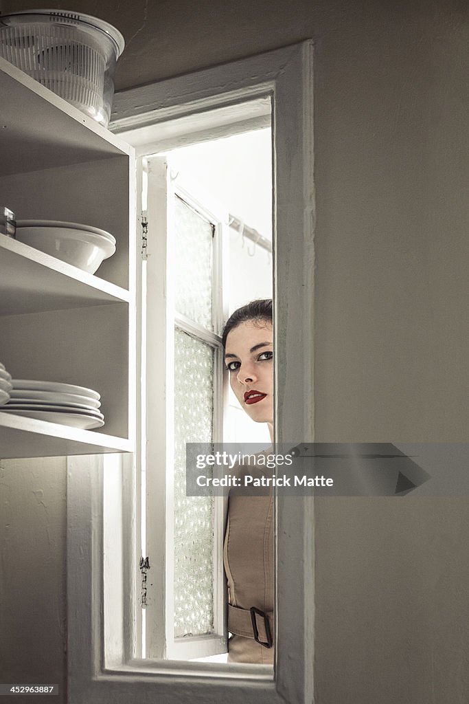 Woman sneak peeking through a window in a kitchen