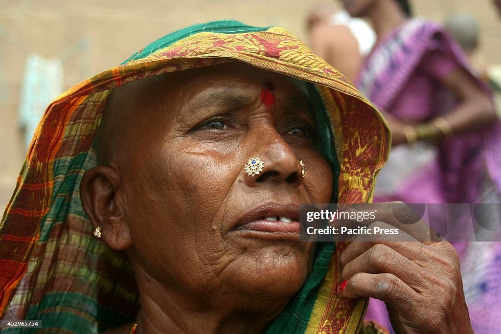 A shaven-headed woman sits on the  Ganga river bank after...