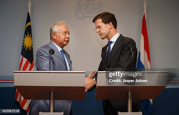 Dutch Prime minister Mark Rutte closes his eyes as he holds hands with Malaysian Prime Minister Najib Razak after they made a statement on July 31,...