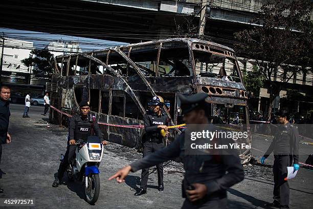 Police inspect a burnt out bus after Anti-government protesters attack pro-government red shirt supporters at Ramkhamhaeng area on December 2, 2013...